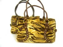 Tiger Pattern Faux Fur fashion handbag has a studded trim in the front, a double handle and a top zipper closure. Belt accents on the sides of the bag. 