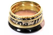 Thick two tone resin bangle with two tribal print bangles comprises this lightweight & trendy costume jewelery set. Three gold colored alloy bangles in varied designs & width are also in this set. Imported.