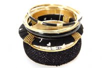 Beautiful five piece cuff bangle set in Black and Gold motifs. This exotic set includes a wide black colored embellished statement piece, a black and gold medium size bangle and additional black and gold thinner pieces. Hand crafted. Imported.