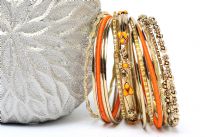 This 15 pieces set of fashion bangles includes one wide patterned bangle with orange beads on it, 2 orange bangles have fabric on it, 2 have metal pattern on it & rest have glitter. 