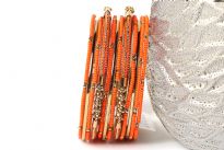 Bright colored elegant looking gold colored metal fashion bangles set of 12 pieces has small orange beads on 7 thin bangles, 3 thin gold colored bangles & 2 are resin bangles encrusted in patterned gold colored metal frame.