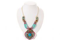 Royal look necklace made of gold tone metal & strands of resin beads has heart shape pendant in gold tone metal with engraved design & decorated with turquoise & red miniature beads. Gold tone chain at the ends with lobster closure completes this necklace.